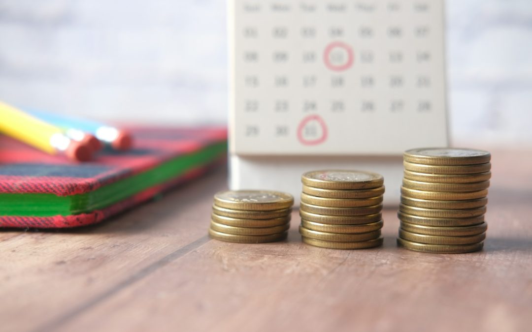 stack of coins and calendar on wooden background